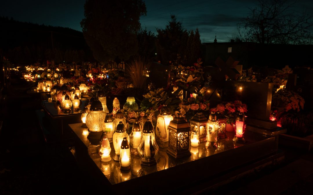 Cimetière illuminé de lanternes et de bougies en soirée, symbole des pratiques funéraires, de la mémoire et des traditions de deuil à travers les cultures.