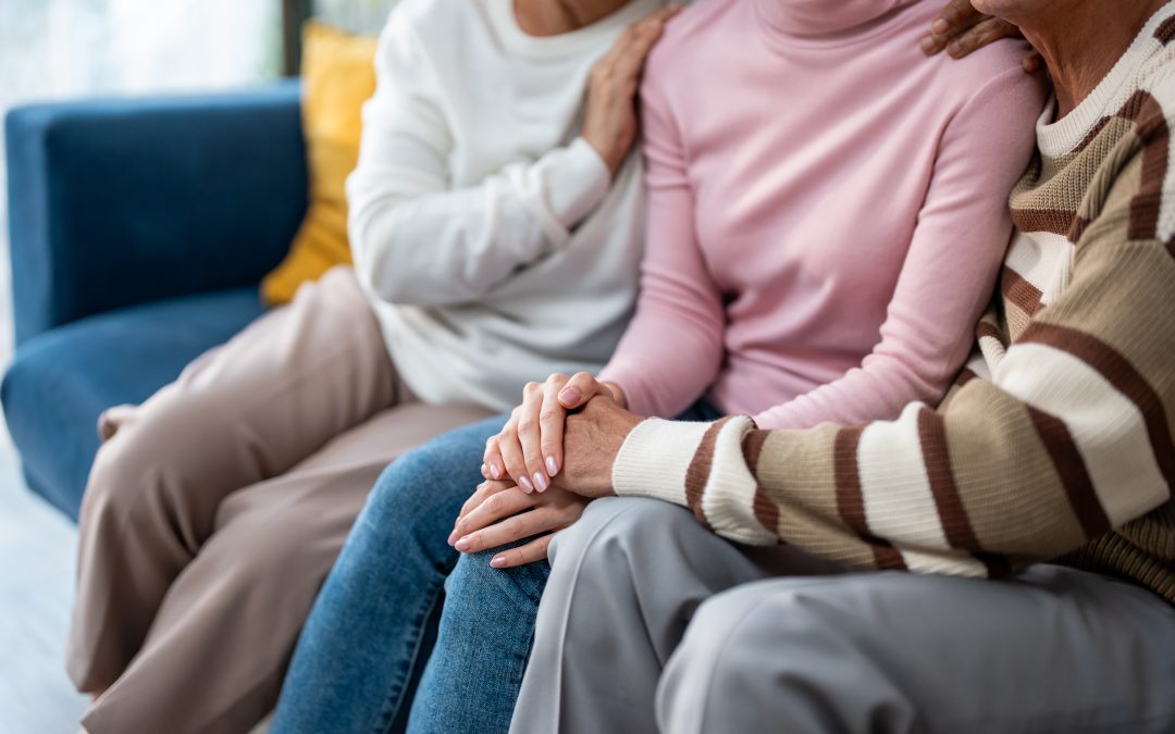 Proches assis ensemble se tenant la main, illustrant le soutien et l’accompagnement des familles dans la durée après un décès