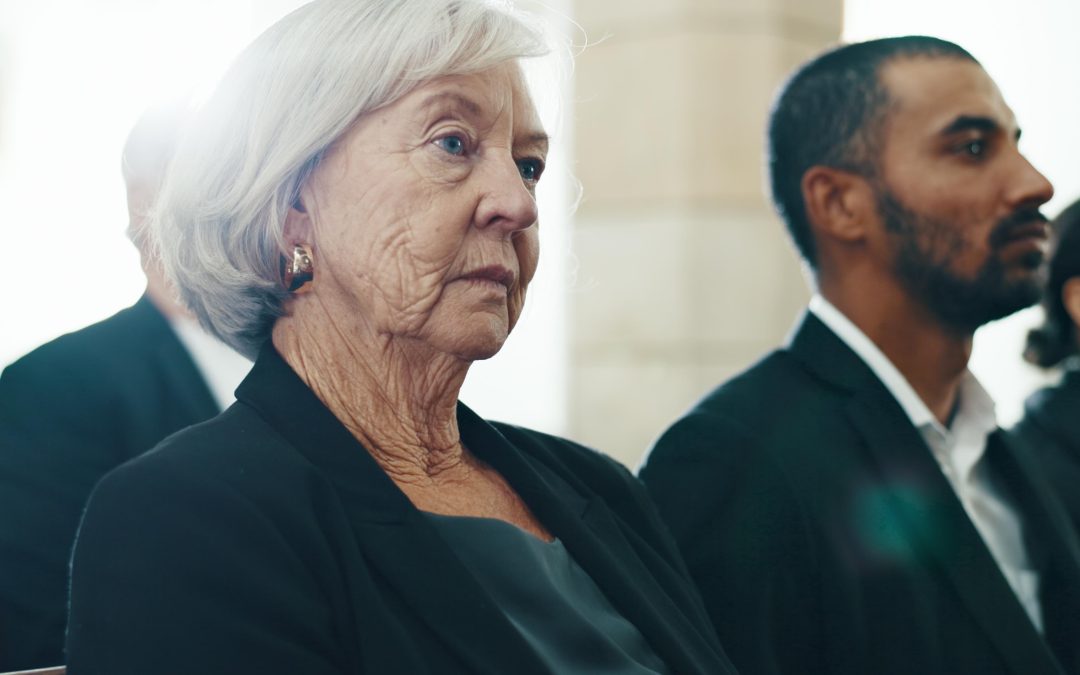 Femme âgée assise lors d’une cérémonie funéraire, illustrant le recueillement et les réalités concrètes à gérer après un décès